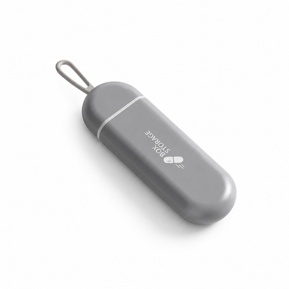 UNTIOR grey pull-out pill case in closed view with compact capsule shape, hanging loop, and BPA-free daily tablet storage design.