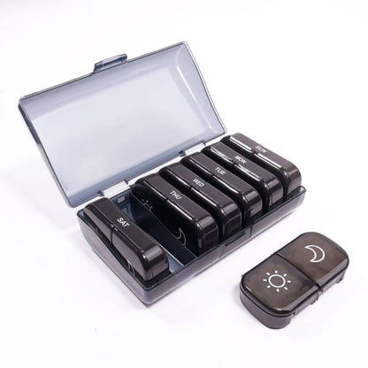 UNTIOR smoky black 14-compartment weekly pill organizer with 7 removable AM/PM daily cases, smoky protective cover, and compact daily case for weekly planning and travel-friendly routines.
